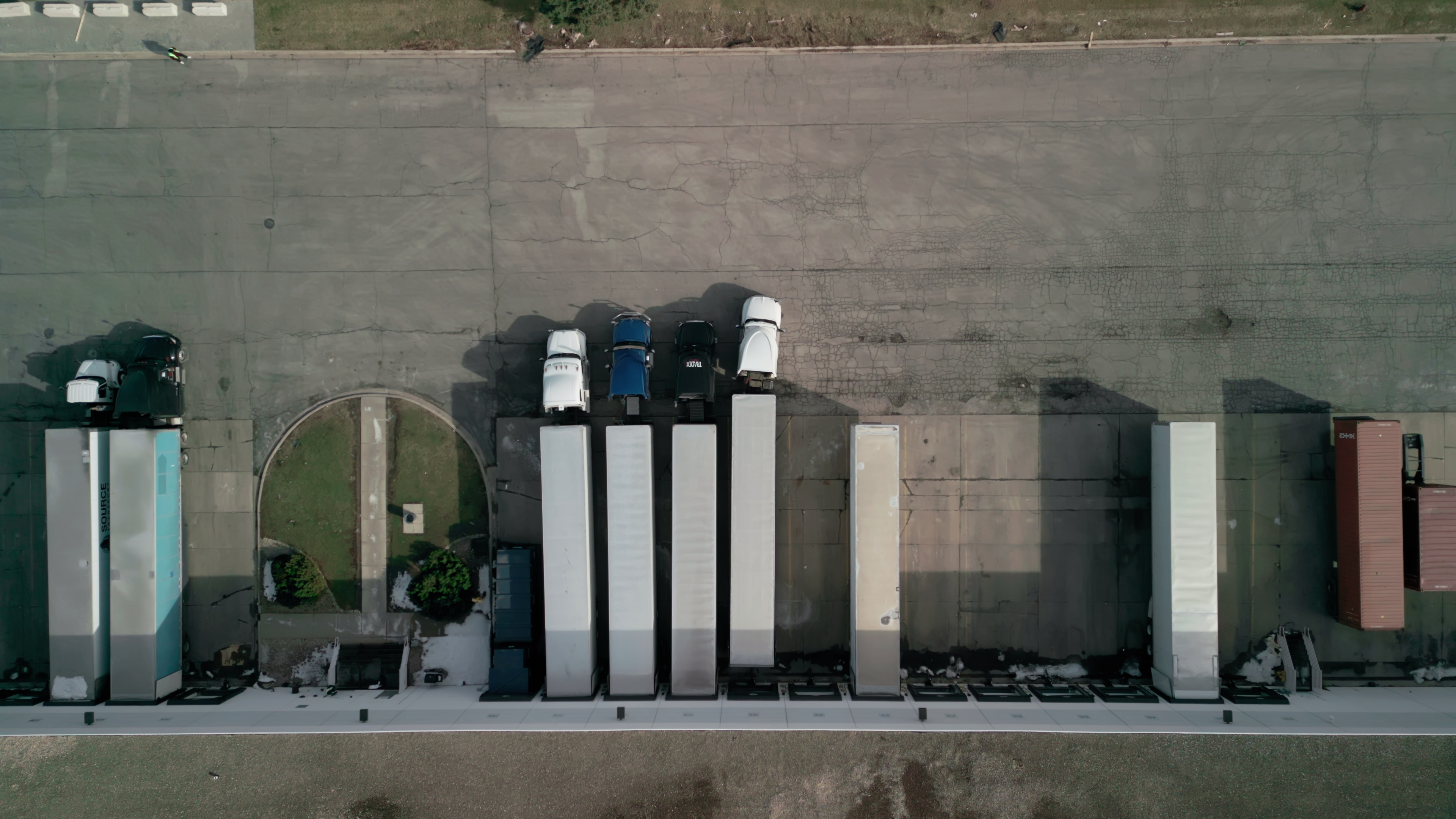 Aerial view of semi-trailers parked at warehouse loading ramps, illustrating cargo-securement inspection focus for Roadcheck 2026
