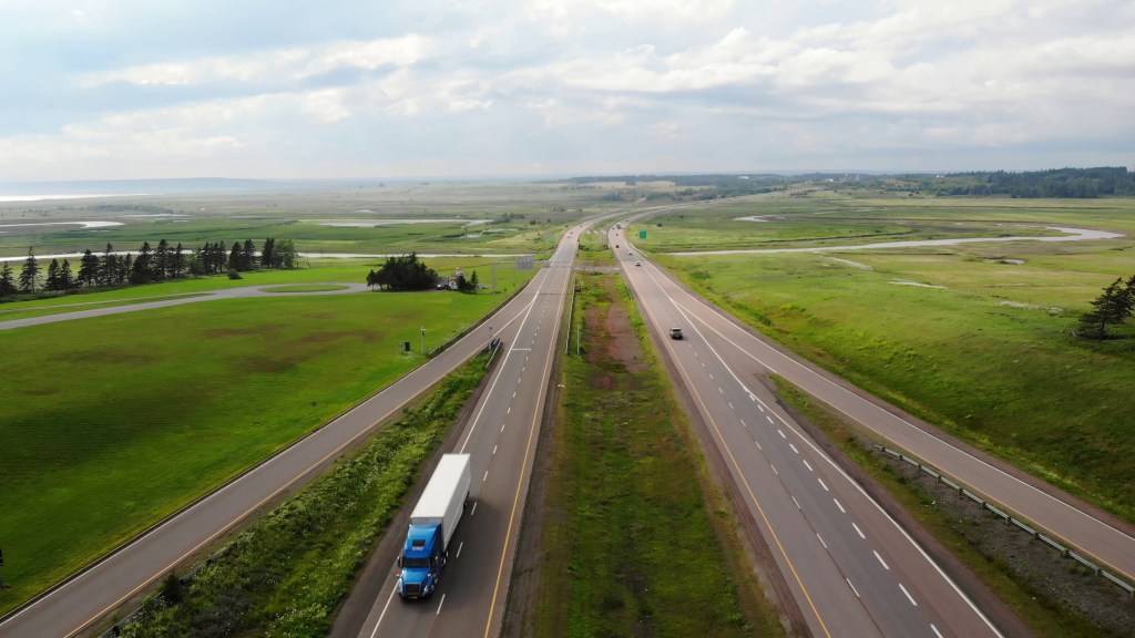 Aerial view of vehicles traveling on a long rural U.S. highway