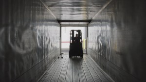 Forklift loading freight cargo into a semi-truck trailer at a distribution center