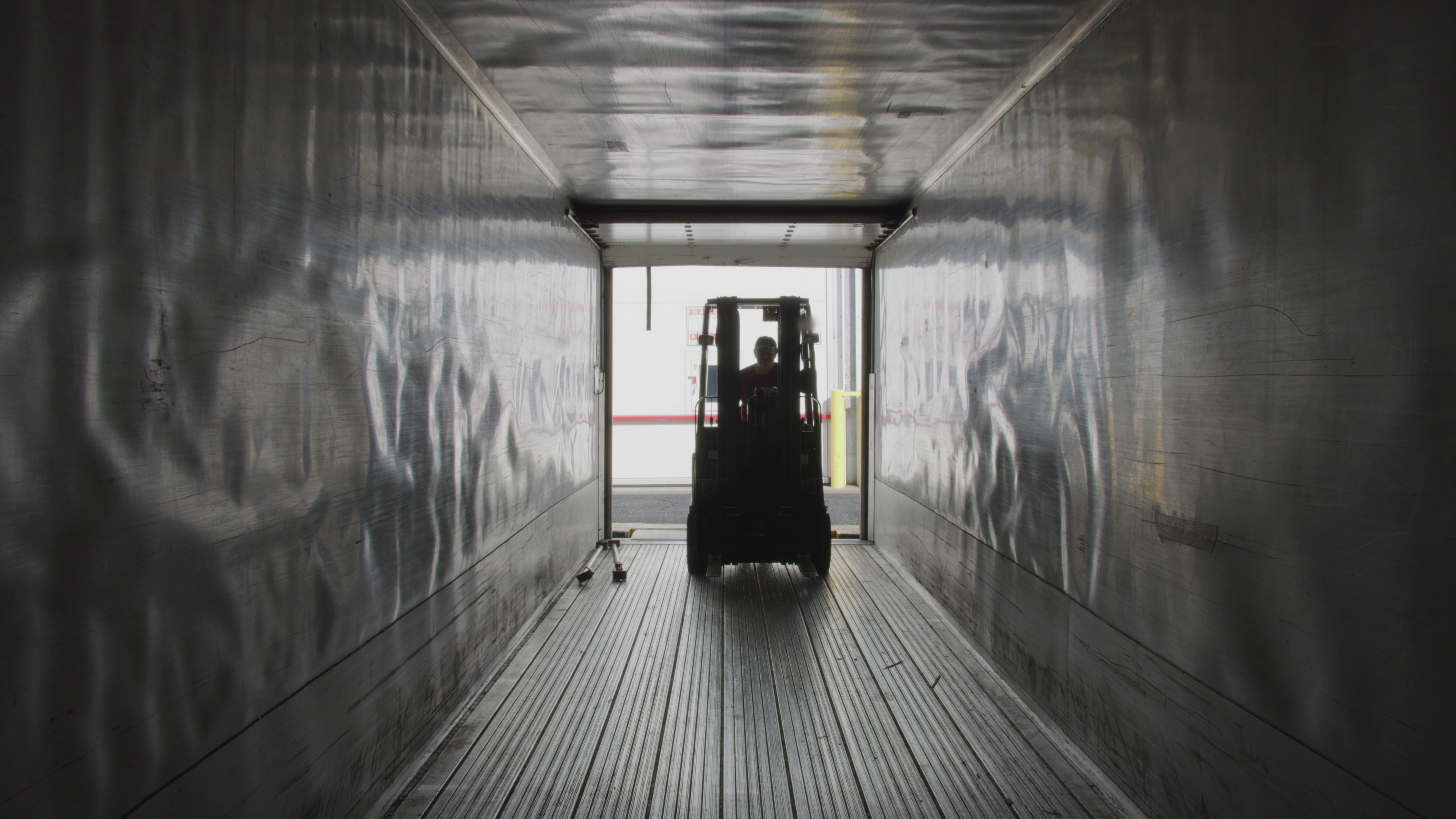 Forklift loading freight cargo into a semi-truck trailer at a distribution center