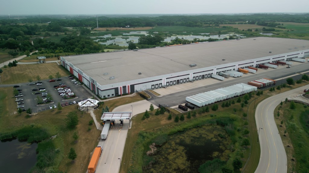 Aerial drone view of a warehouse with semi-trucks and cargo trailers